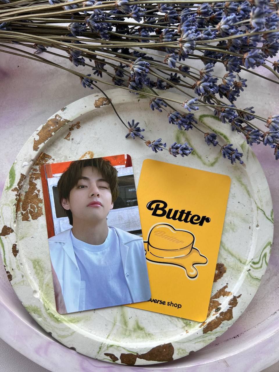 Фотокартка учасника BTS та жовта картка з логотипом синглу Butter від Weverse Shop на декоративній тарілці з лавандою