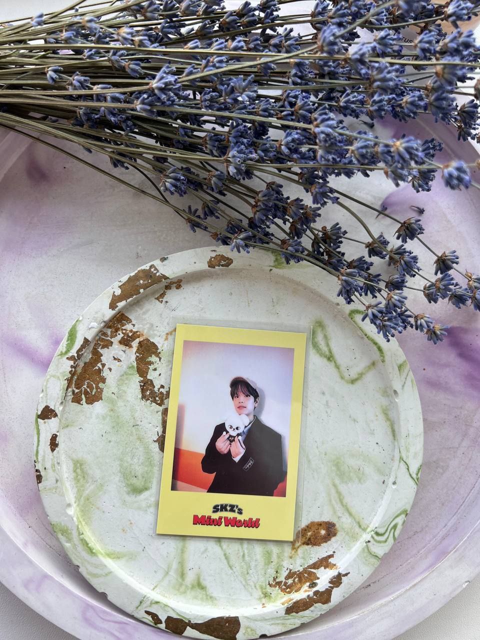 Фотокартка SKZ's Mini World із учасником Stray Kids на декоративній тарілці поруч із сухою лавандою