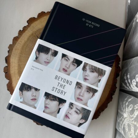 Книга «Beyond the Story: 10-Year Record of BTS» авторства Мьонсок Кан на дерев'яній підставці