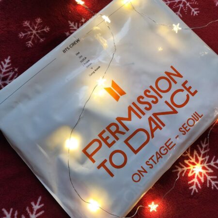 Пакет з мерчем BTS «Permission to Dance On Stage – Seoul» на червоному тлі зі сніжинками та гірляндою