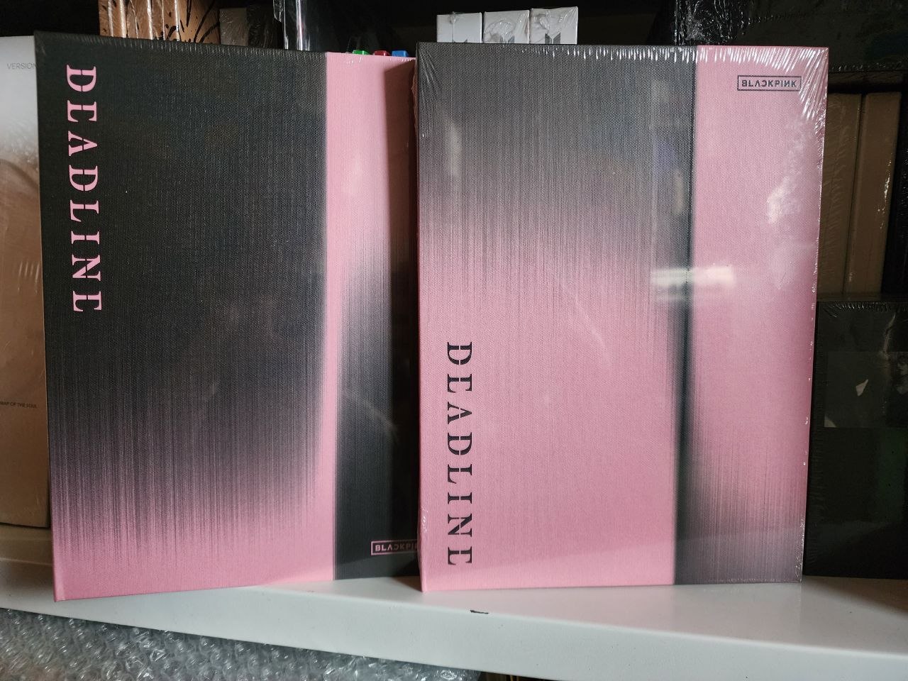 Два видання фотокниги BLACKPINK Deadline: чорна та рожева версії в упаковці на полиці