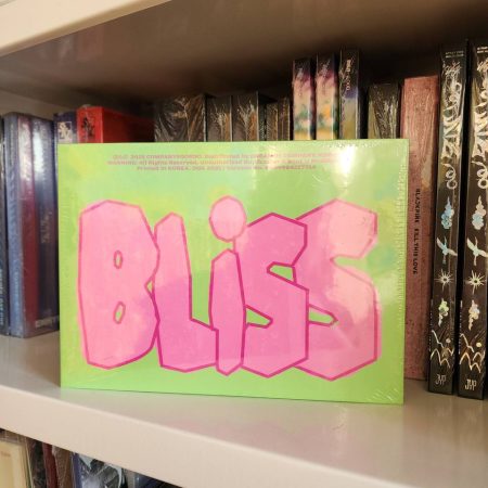 Альбом BLISS у зеленій обкладинці з рожевим написом на полиці поряд з іншими K-pop альбомами